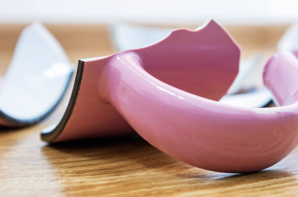 Broken ceramic cup on a wooden floor. Closeup, selective focus